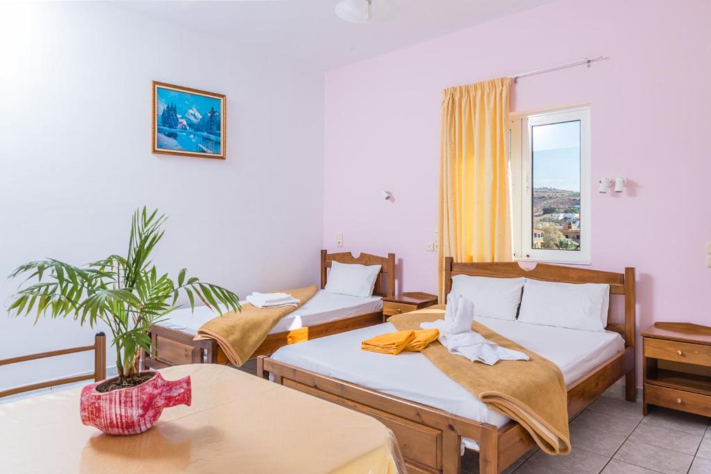 a hotel room with three beds and a window at Arsinoi Studios and Apartments in Kalamaki