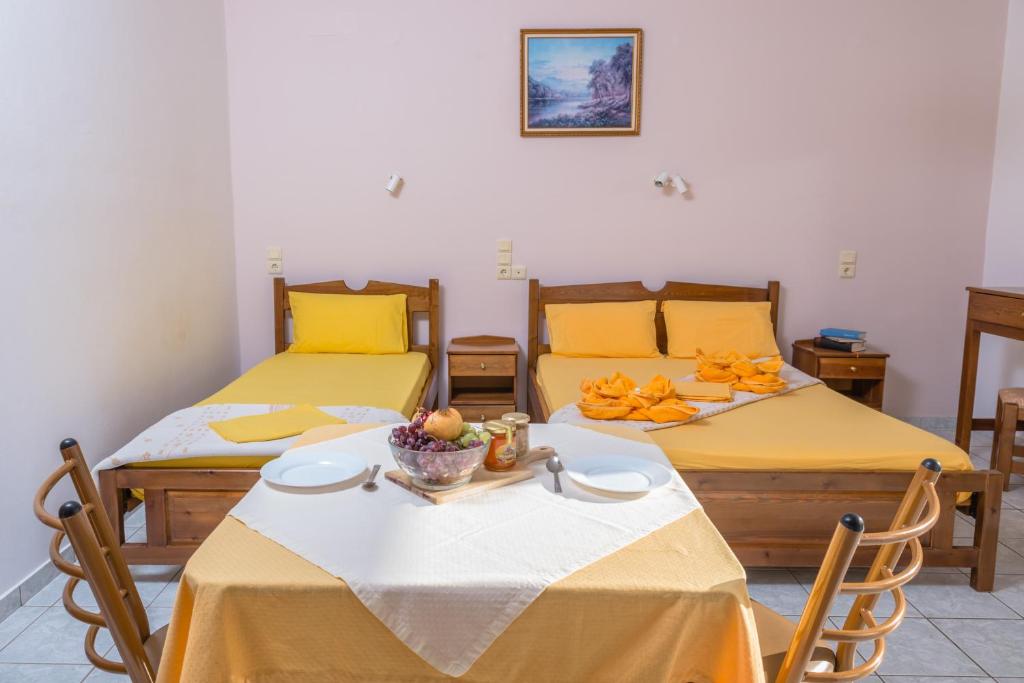 a room with two beds and a table with a bowl of fruit at Arsinoi Studios and Apartments in Kalamaki Heraklion