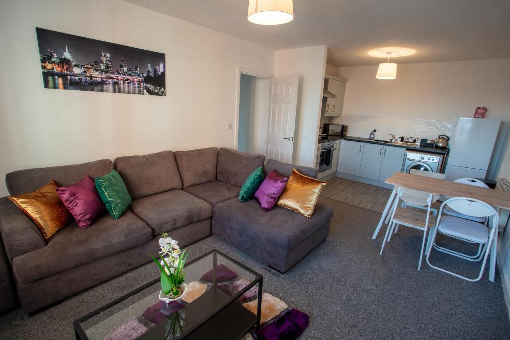 a living room with a couch and a table and a kitchen at Cherry Tree, Centrally Located Warrington Town Centre in Warrington