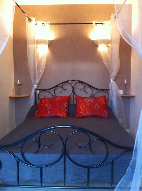 a bed with two red pillows in a room at Chambre d'hôtes La Cavaille in Veyrines-de-Vergt