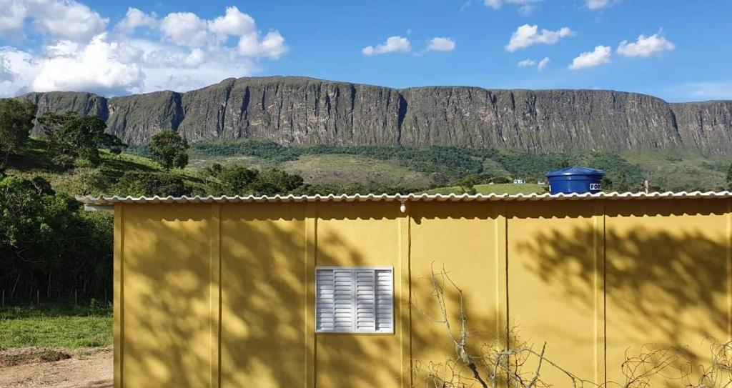 um edifício amarelo com uma janela e montanhas ao fundo em CASA GIRASSOL-Trilha das Flores-SERRA DA CANASTRA em São Roque de Minas