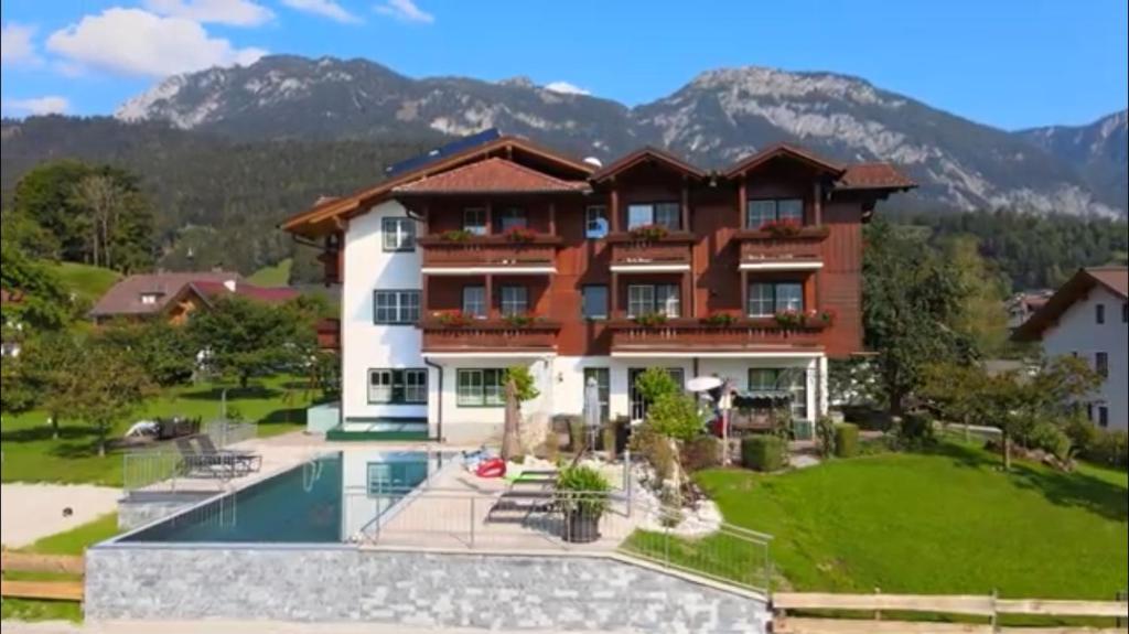 a house with a pool and mountains in the background at Gästehaus Hartweger in Haus im Ennstal