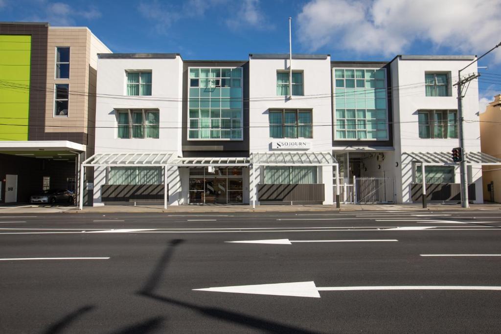 an empty street in front of a white building at Sojourn Apartment Hotel - Riddiford in Wellington