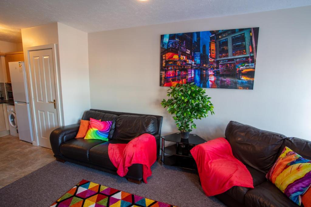 uma sala de estar com 2 sofás de couro com almofadas coloridas em Ample Comforts, Centrally Located, Town Centre em Warrington