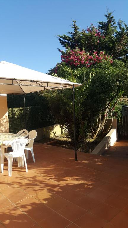 patio z 2 białymi krzesłami i parasolem w obiekcie Casa Vacanza Santorsola w mieście Trinità dʼAgultu
