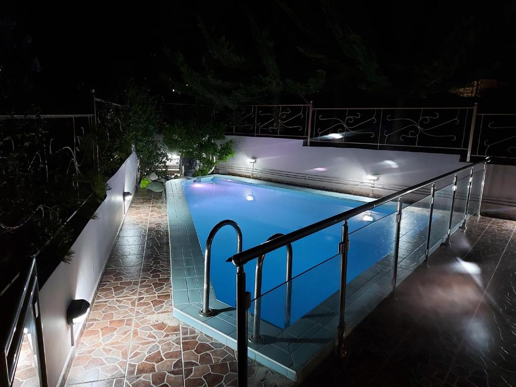 una piscina por la noche con luces en Violet Studio με πισίνα, en Volos