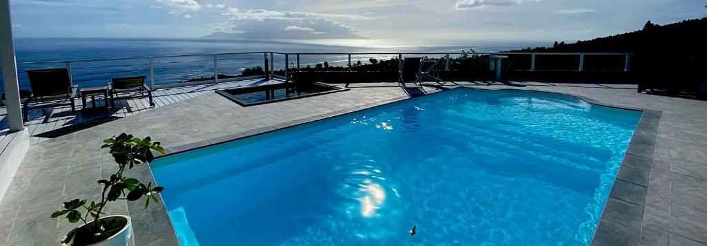 a beach with a pool and a balcony overlooking the ocean at Ninamu Pearl Guest House in Punaauia