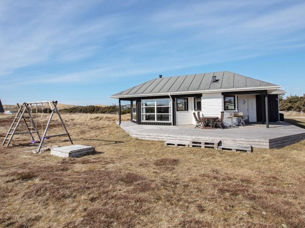a small house with a deck and a swing at 8 person holiday home in Harbo re in Harboør