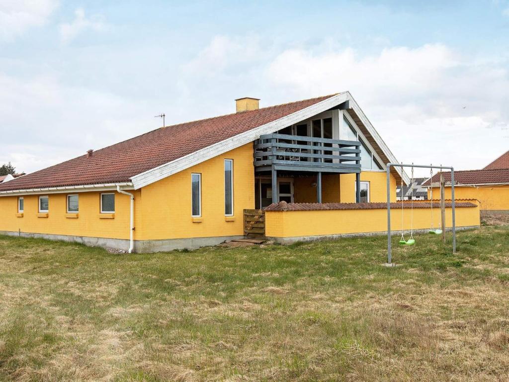 un bâtiment jaune dans un champ d'herbe dans l'établissement 10 person holiday home in Thisted, à Nørre Vorupør