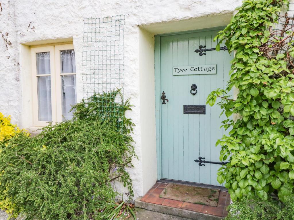 a blue door on a white house with a window at Tyee Cottage in Carnforth