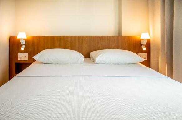 un grande letto bianco con due cuscini in una camera da letto di Salinas Exclusive Resort a Salinópolis