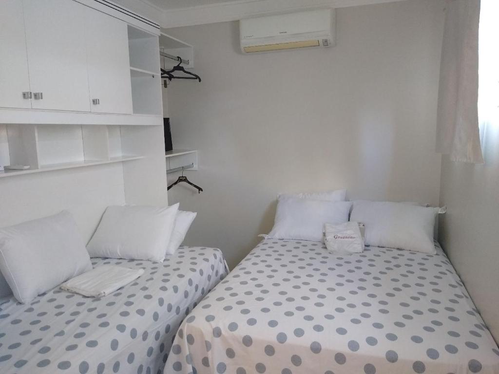 two beds in a small room with white walls at Apartamentos aconchegantes in Teresina