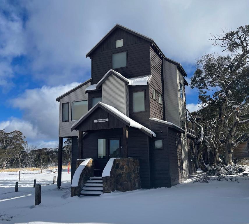 a black house with snow on the ground at Alpine Edge in Dinner Plain