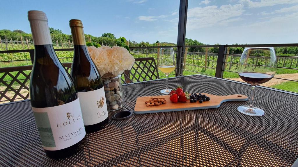 Collis winery - Family & Friends - Mobilhome في روفينج: زجاجتان من النبيذ وصحن من الفاكهة على الطاولة