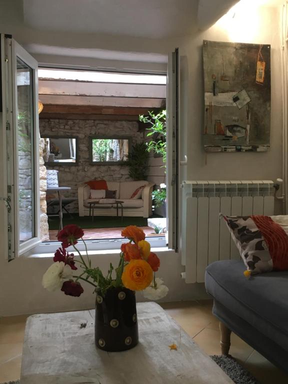 a vase with flowers on a table in a living room at La 54 Provence in LʼIsle-sur-la-Sorgue