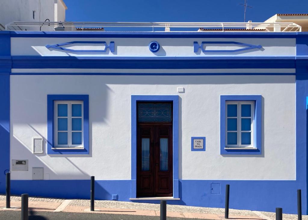 een blauw-wit gebouw met een deur en twee ramen bij Casa da Praia in Albufeira