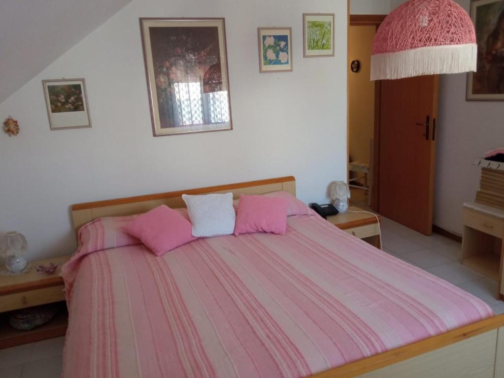uma cama rosa com almofadas cor-de-rosa num quarto em Carmen House em Grottammare
