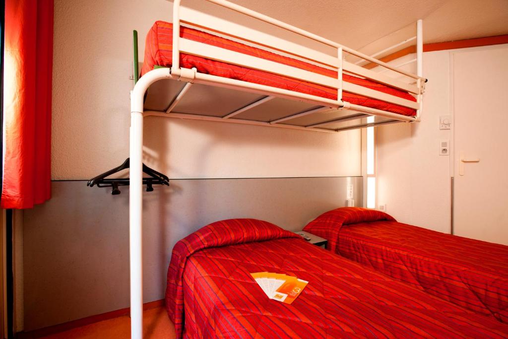 two bunk beds in a room with red sheets at Premiere Classe Epinal in Épinal