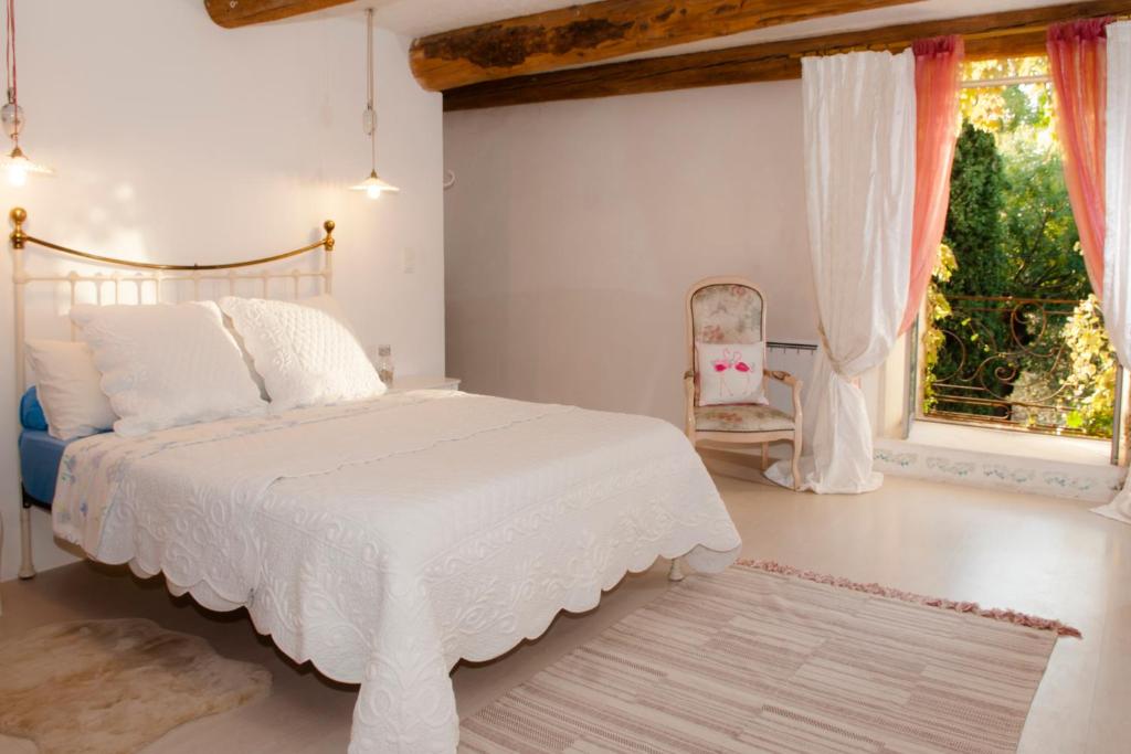 1 dormitorio con cama blanca y ventana en Sinti, en Saint-Hilaire-dʼOzilhan