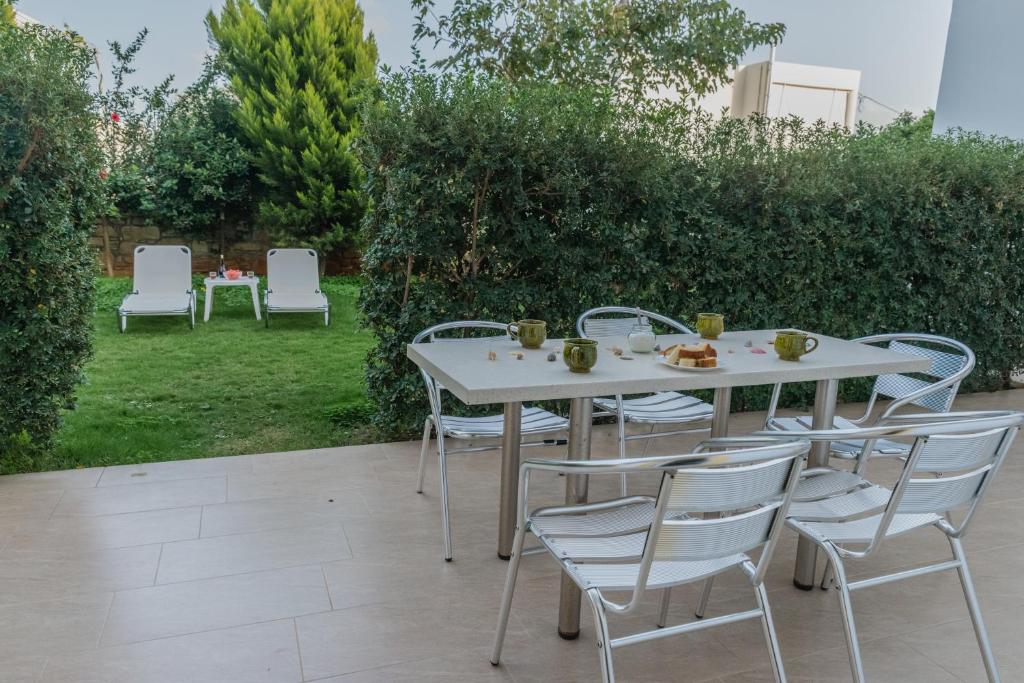 a white table and chairs in a garden at Arsinoi Studios and Apartments in Kalamaki