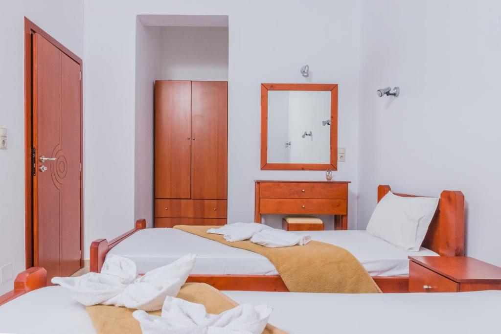 a bedroom with two beds and a dresser and a mirror at Arsinoi Studios and Apartments in Kalamaki