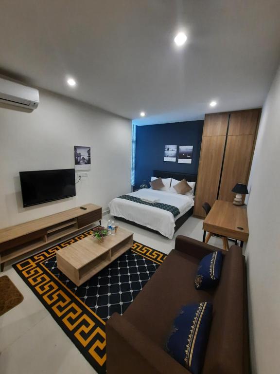 a bedroom with a bed and a couch and a tv at Arena SOHO Kuching with infinity rooftop pool and free WiFi in Kuching