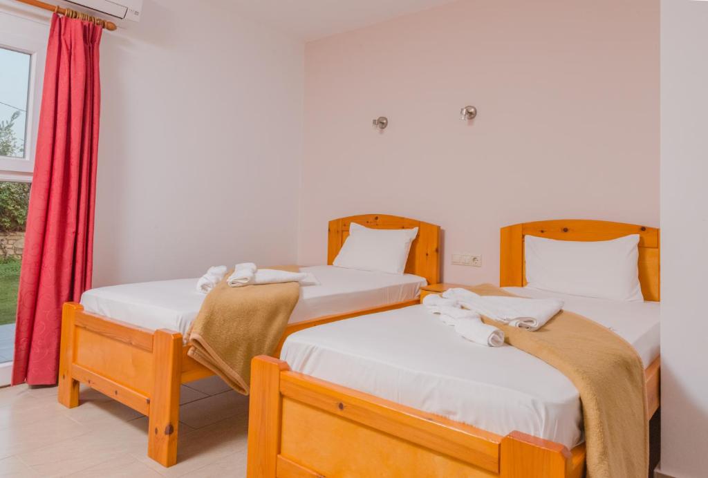 two twin beds in a room with a window at Arsinoi Studios and Apartments in Kalamaki