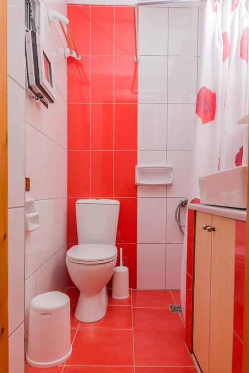 a red and white bathroom with a toilet and a sink at Arsinoi Studios and Apartments in Kalamaki