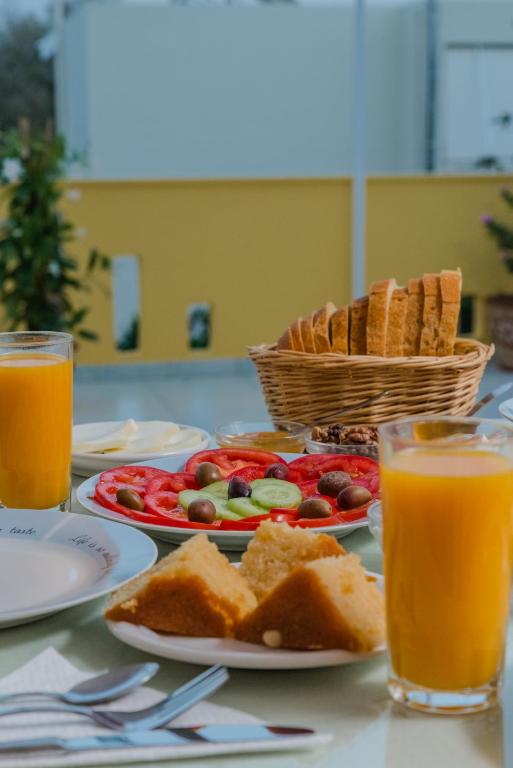 a table with plates of food and glasses of orange juice at Arsinoi Studios and Apartments in Kalamaki