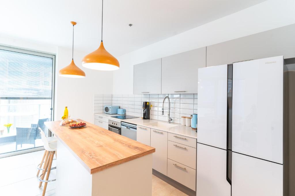 a kitchen with white appliances and a wooden counter top at Deluxe Apartment in Top Tel Aviv Neighbourhood by Sea N' Rent in Tel Aviv