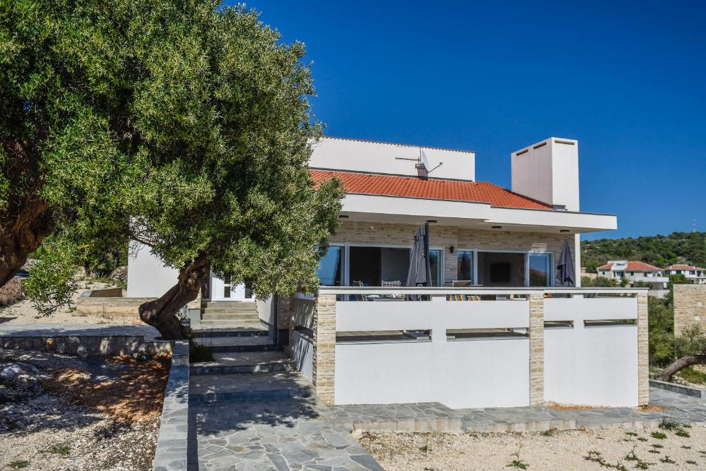 a white house with a tree in front of it at Moderner Bungalow mit Meerblick in Lun