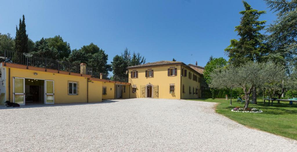 une grande maison jaune avec une allée en gravier dans l'établissement Bed&Breakfast Il Frantoio, à Misano Adriatico