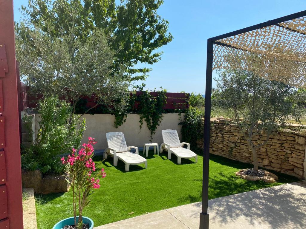 einen Hinterhof mit zwei Stühlen und einen Garten mit Gras in der Unterkunft La Vigne in Saint-Just