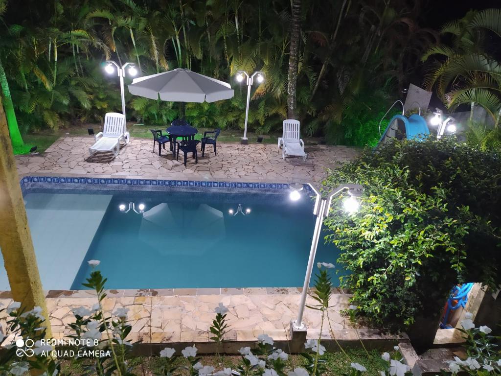 - une piscine de nuit avec une table, des chaises et un parasol dans l'établissement Sobrado Igarata, à Igaratá