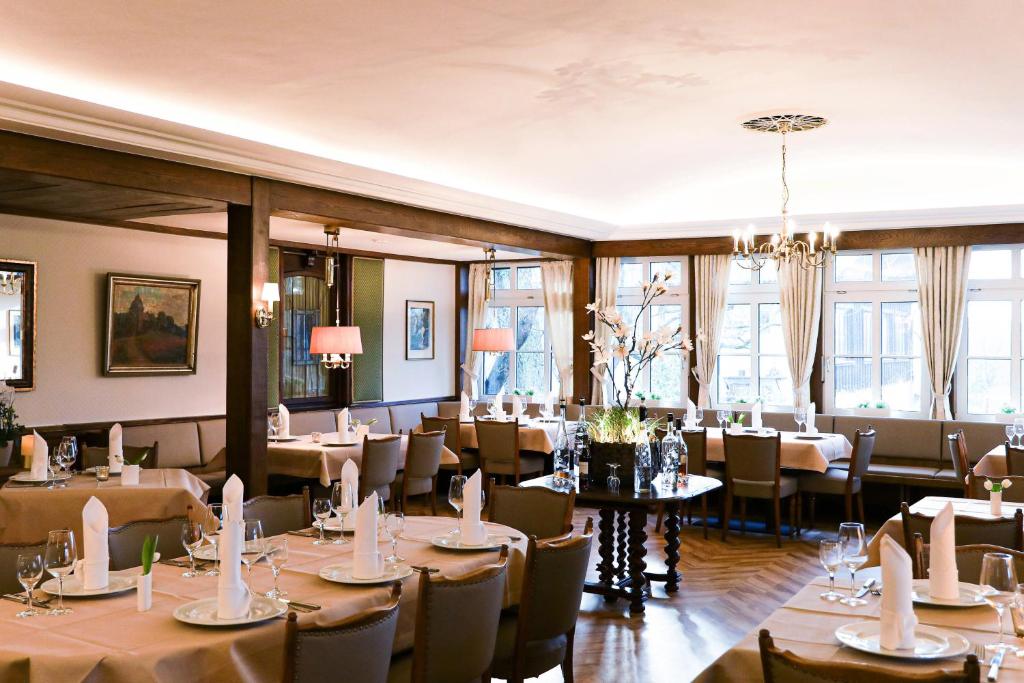 a dining room with tables and chairs and windows at Landhotel Bonsmann's Hof in Herdecke