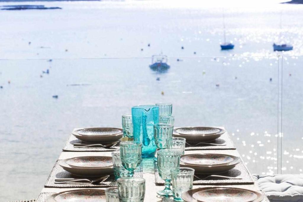 a table with plates and glasses on top of the water at Beachfront Es Turo in Colonia Sant Jordi