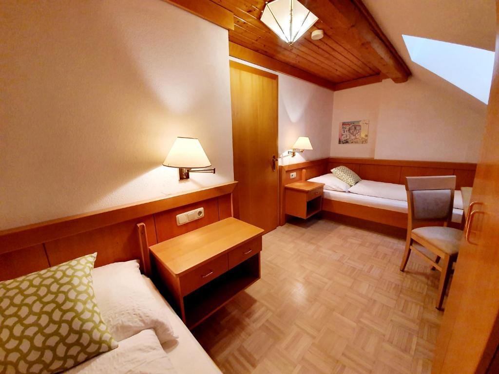 a small room with a bed and a desk and a table at Gasthof Thomann in Velden am Wörthersee