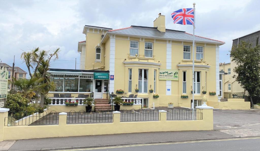 ein gelbes Gebäude mit einer Flagge darüber in der Unterkunft Paignton Court in Paignton