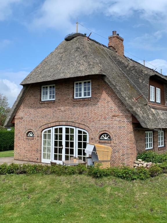 a large brick house with a thatched roof at Ferienhaus Honigklee im Lüüvhoog in Keitum
