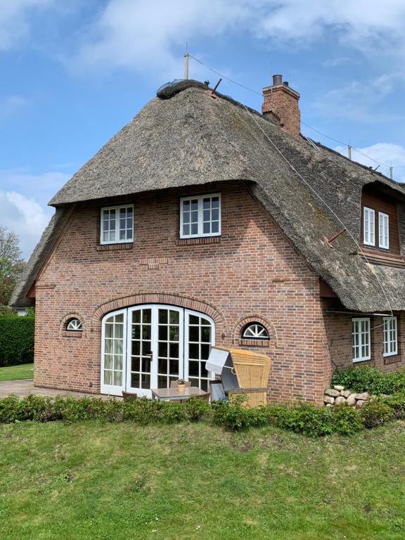 ein großes Backsteinhaus mit einem Strohdach in der Unterkunft Ferienhaus Honigklee im Lüüvhoog in Keitum