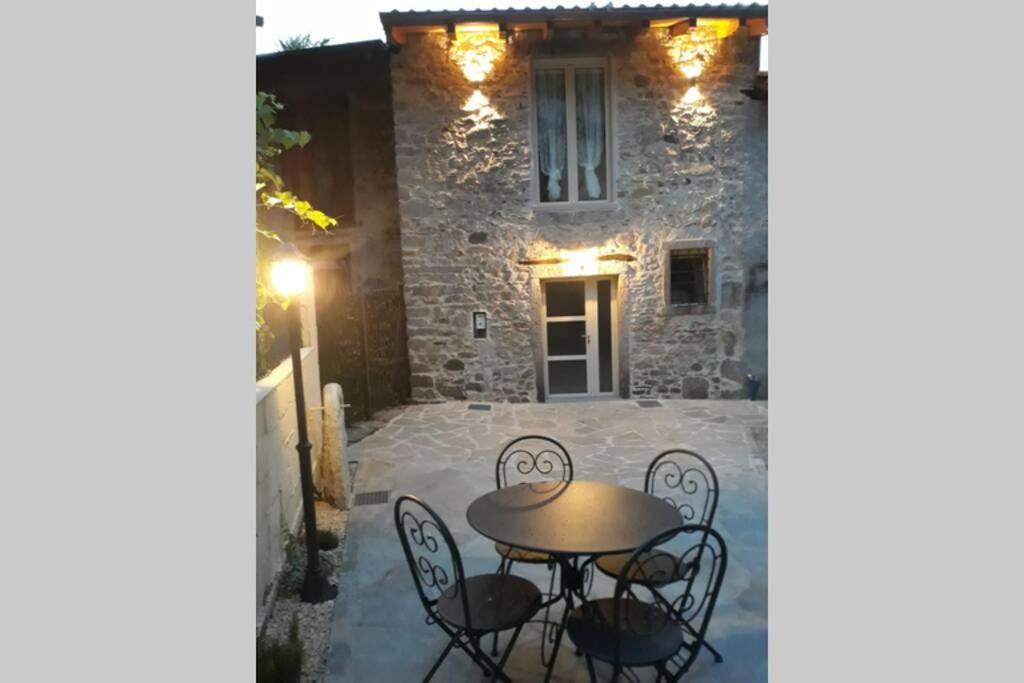 patio ze stołem i krzesłami przed budynkiem w obiekcie Serenity Cottage Baveno w mieście Baveno
