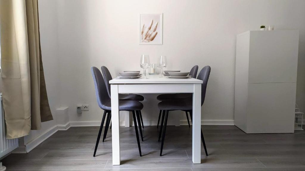 einen weißen Tisch mit Stühlen und Weingläsern darauf in der Unterkunft Moderne City Apartments im Stadtzentrum in Kiel