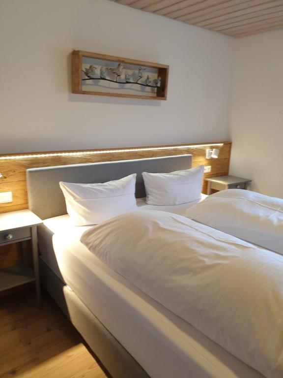 a bed with white sheets and pillows in a room at Gästehaus Bartlehof in Schluchsee