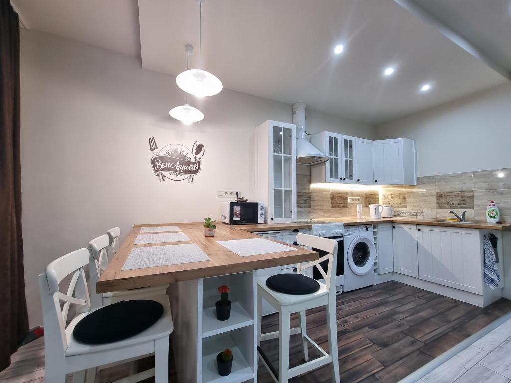 米什科爾茨的住宿－HIGH STREET APARTMAN，厨房配有木桌和白色橱柜。