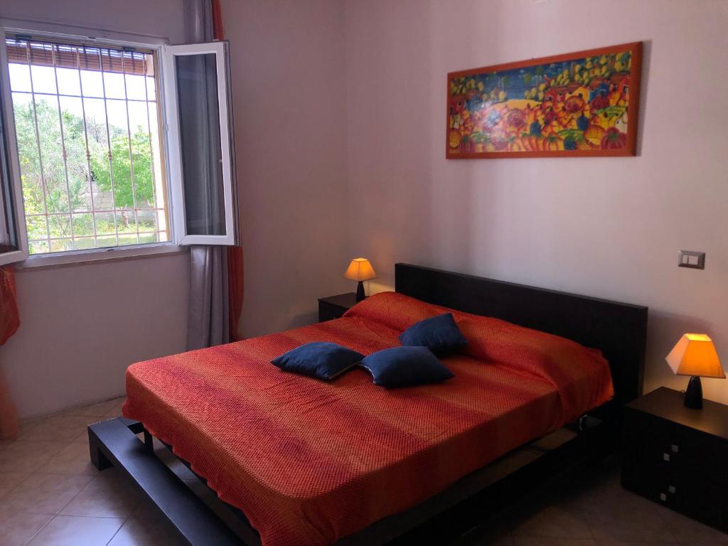 1 dormitorio con 1 cama roja y 2 almohadas azules en Relax Torre lapillo, en Torre Lapillo