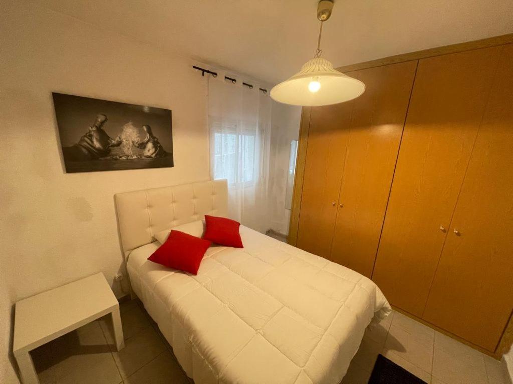 una camera con un letto bianco con due cuscini rossi di Valdavia Habitaciones a Madrid