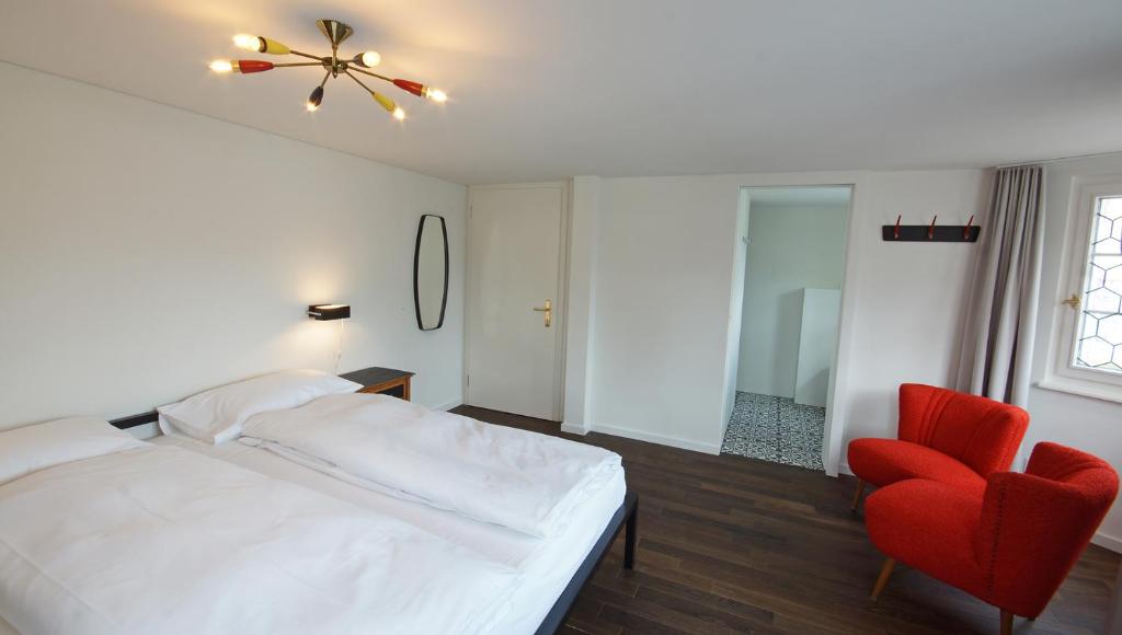 アッペンツェルにあるAlte Metzg - Boutique Pensionのベッドルーム(白いベッド1台、赤い椅子付)