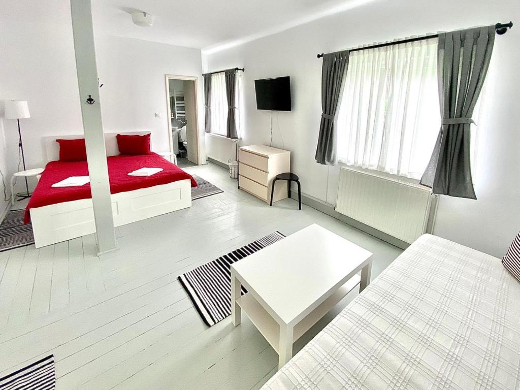 Habitación blanca con cama roja y sofá en Casa Ghioceilor, en Vatra Dornei