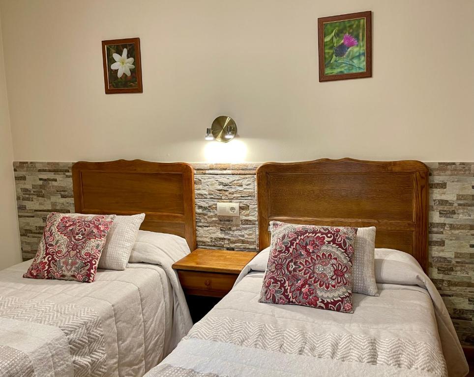 1 dormitorio con 2 camas y una lámpara en la pared en Hotel Rural Peña Castil, en Sotres