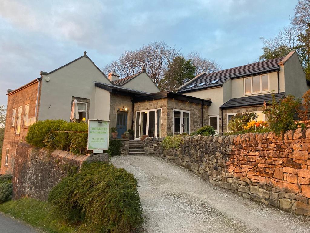 a house with a stone wall next to a street at The Gables Bed & Breakfast in Matlock